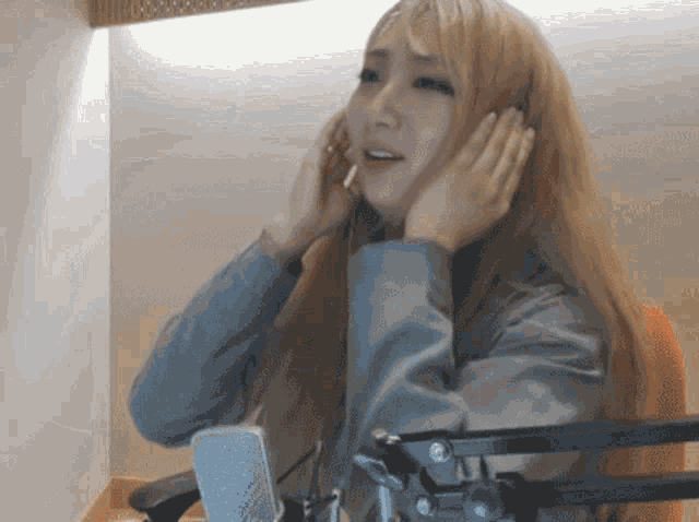 a woman with long blonde hair is sitting in front of a microphone