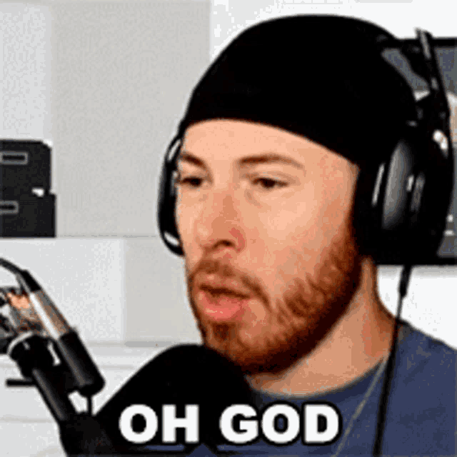 a man wearing headphones and a hat is talking into a microphone .