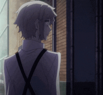a man in a suit and suspenders is standing in front of a brick building