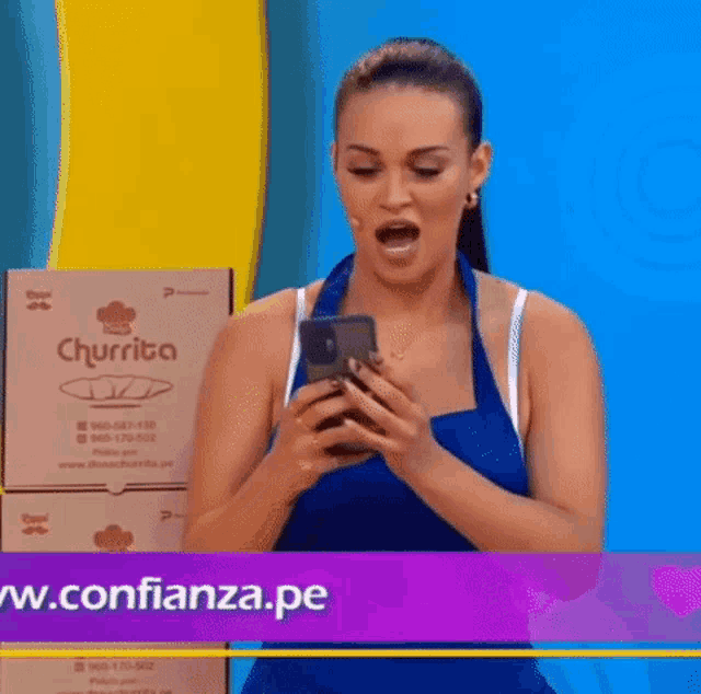 a woman is holding a cell phone in front of a box that says churrita on it .