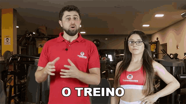 a man and a woman are standing in a gym and the man is wearing a red shirt that says treinomastery