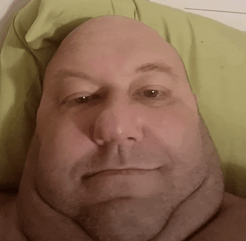 a close up of a man 's face with a green pillow around his neck