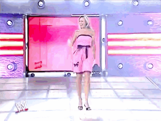 a woman in a pink dress is standing on a stage in front of a sign that says w.