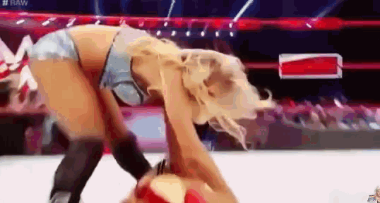 a woman in a bikini is wrestling another woman in a ring .