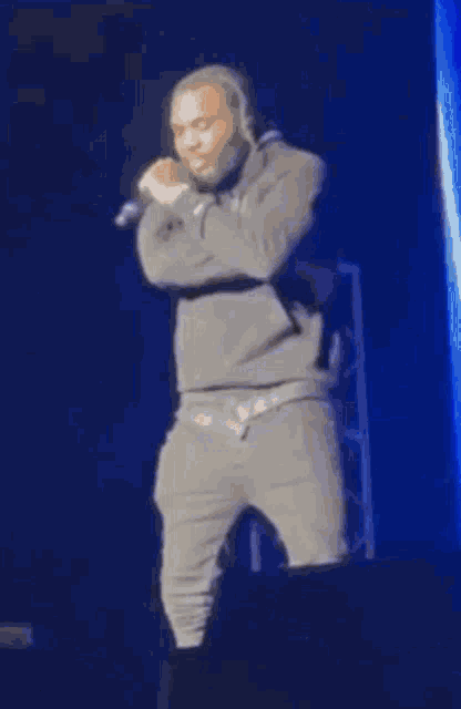 a man is standing on a stage holding a microphone in his hand and singing into it .
