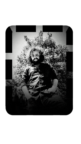 a man with a beard is sitting in front of a tree