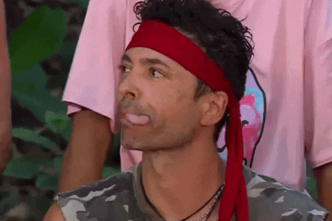 a man wearing a red headband and a camouflage shirt is making a funny face .