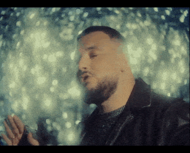 a man with a beard is singing in front of a window