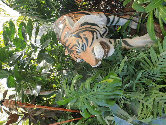 a statue of a tiger is surrounded by lots of greenery