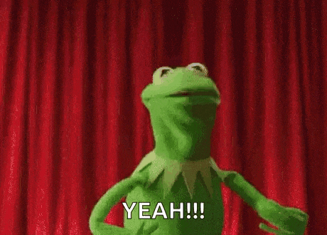 kermit the frog is dancing on a stage in front of a red curtain and saying yeah .
