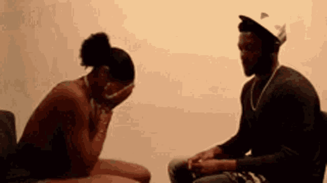 a man and a woman are sitting next to each other . the woman is covering her face with her hands .