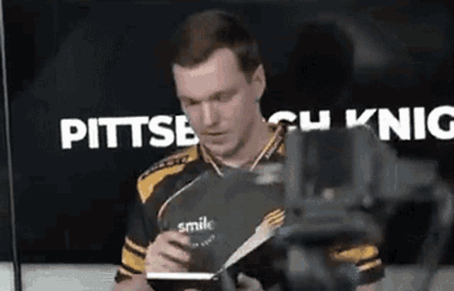 a man in a pittsburgh cu knic jersey is holding a book