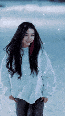 a woman wearing a white sweater and black pants is standing in the snow