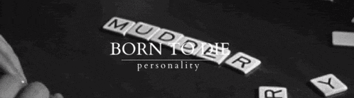 a black and white photo of a person playing scrabble with the words born to be personality on the bottom