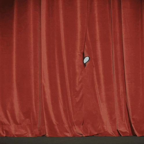 a cartoon character in a tuxedo and bow tie stands in front of a red curtain