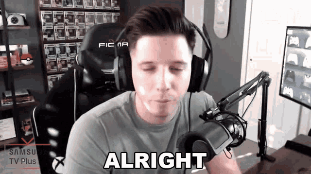 a man wearing headphones is sitting in front of a microphone and saying alright