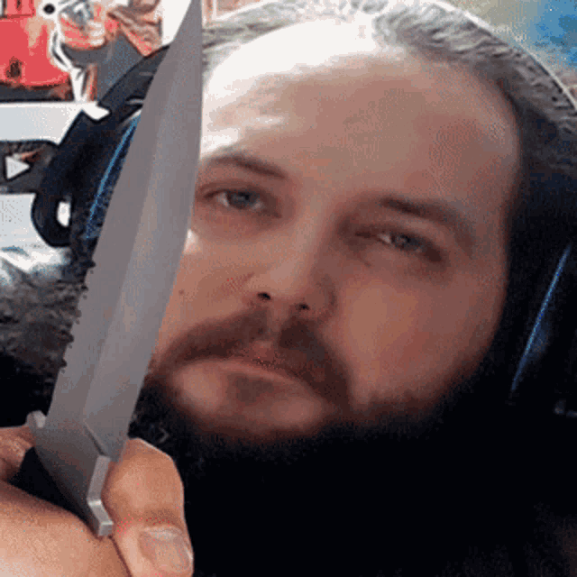 a man with a beard is holding a large knife