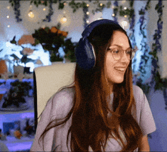a woman wearing headphones and glasses is smiling in front of flowers