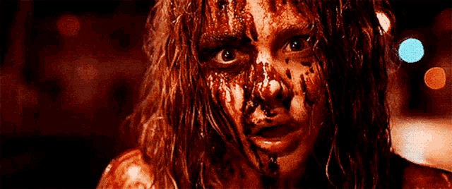 a woman with blood on her face is looking at the camera .