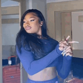 a woman in a blue crop top is holding a pair of scissors in her hand .