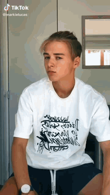 a young man wearing a white t-shirt that says tiktok