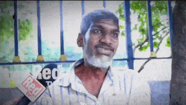 a man with a beard is being interviewed by a red tv reporter .