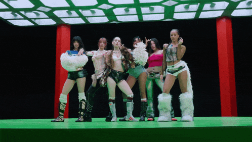 a group of women are standing on a stage with a green background