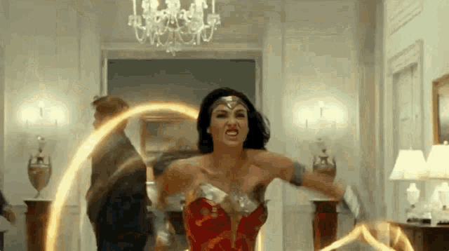 a woman in a wonder woman costume is standing in a room holding a light .