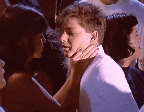 a woman holds a man 's neck in a crowded room
