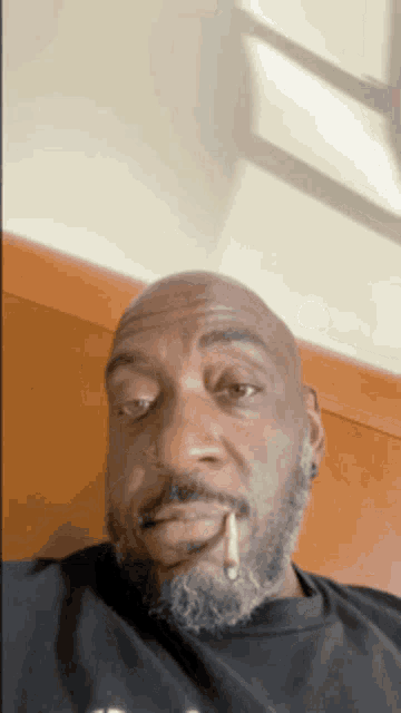 a bald man with a beard is smoking a cigarette in his mouth