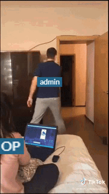a man in a blue shirt is standing in front of a laptop with the word admin on it