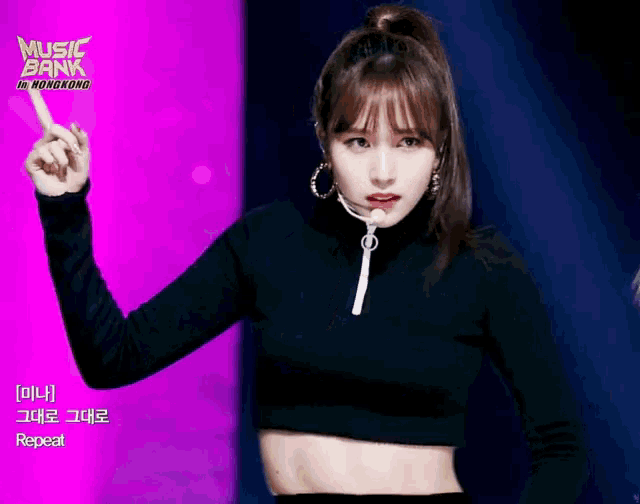 a woman in a black crop top stands in front of a music bank in hong kong banner