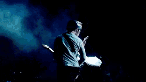 two men are playing guitars on a stage in front of a crowd of people