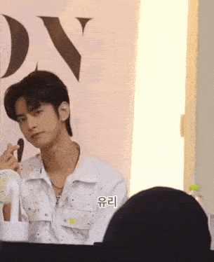 a man is applying makeup in front of a sign that says dx