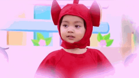 a little girl wearing a red devil costume with horns