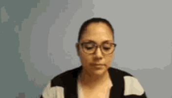 a woman wearing glasses and a sweater is making a funny face .