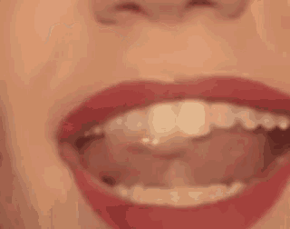 it is a close up of a woman 's mouth with red lipstick and white teeth .
