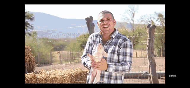 a man in a plaid shirt is holding a small pig