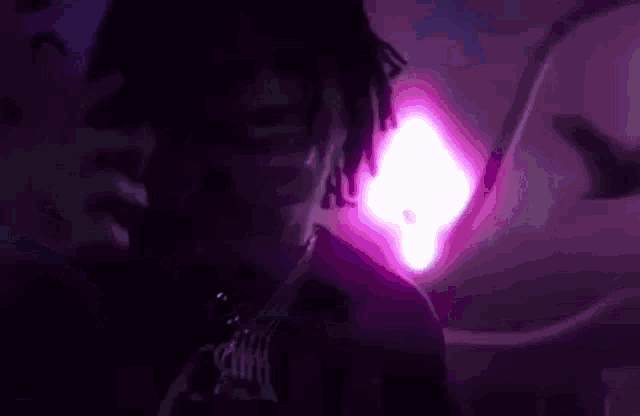 a close up of a person 's face with a purple light behind them .