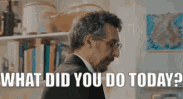 a man in a suit and tie is standing in front of a bookshelf and saying `` what did you do today ? ''