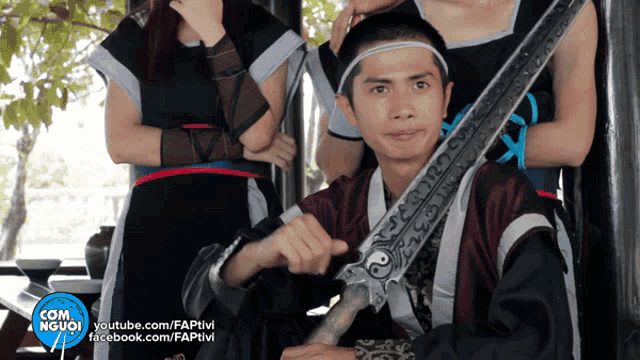 a man holding a sword in front of a group of people with com người written on the bottom left