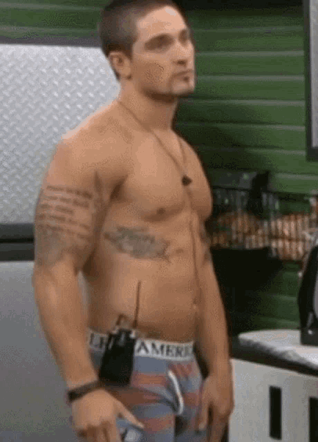 a shirtless man wearing american eagle underwear stands in a kitchen