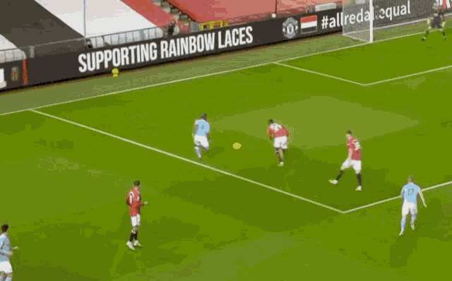 a soccer field with a banner that says supporting rainbow laces on it