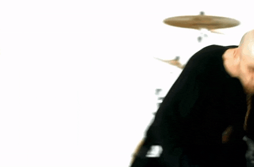a man in a black shirt is playing drums in a blurry photo