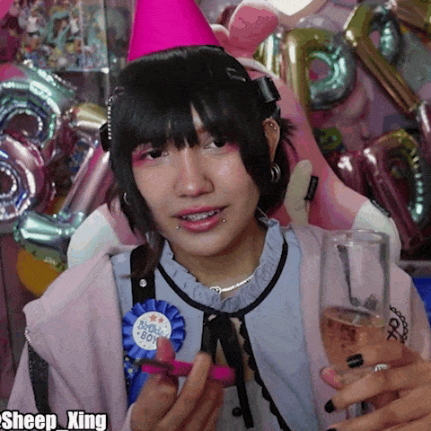 a woman wearing a pink party hat and holding a glass of champagne