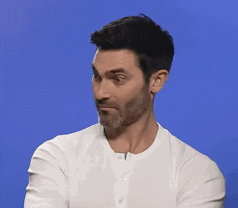 a man with a beard is wearing a white shirt with his arms crossed .