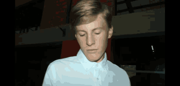 a young man wearing a white shirt looks down at something