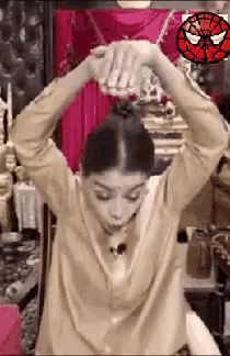 a woman is holding her hair in a bun with a spider man logo in the background .