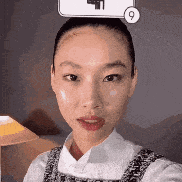 a close up of a woman 's face with a number 9 on her head