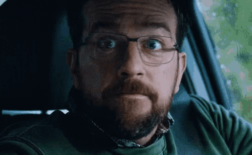 a man with glasses and a beard is sitting in a car